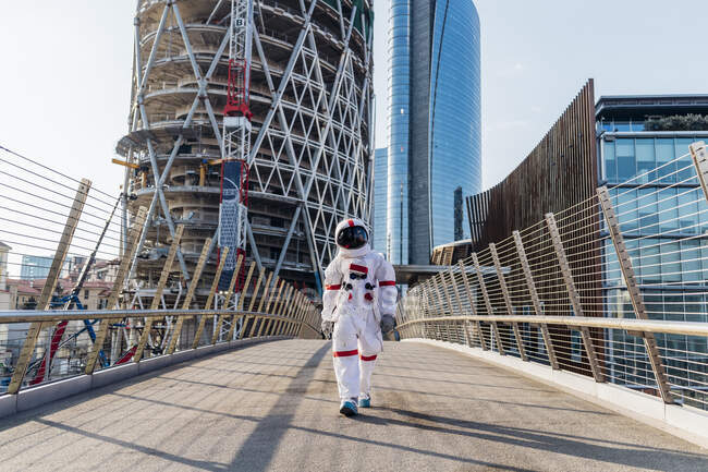 Mid adult astronaut wearing space suit walking on bridge during sunny day — Stock Photo
