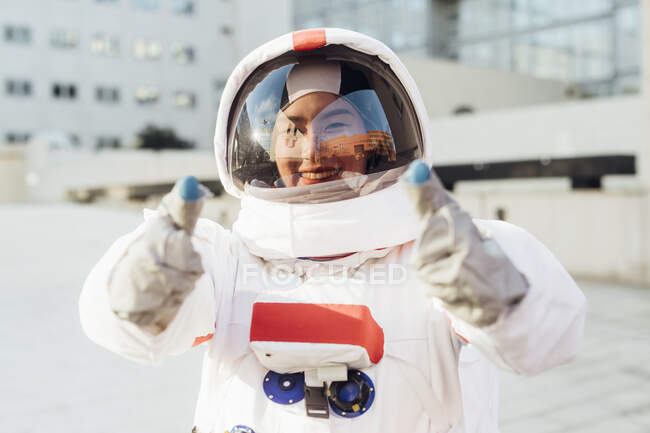 Mujer astronauta feliz en traje espacial haciendo gestos al aire libre - foto de stock