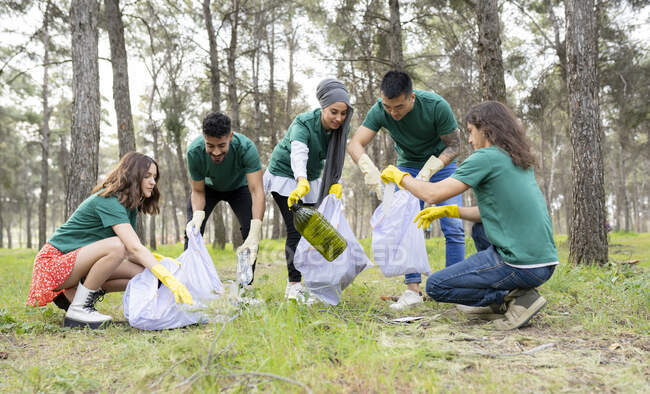 Amigos ecologistas recogiendo basura plástica en el bosque - foto de stock