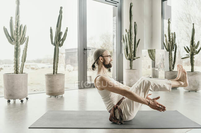 Male yoga teacher practicing body balance on exercise mat — Stock Photo