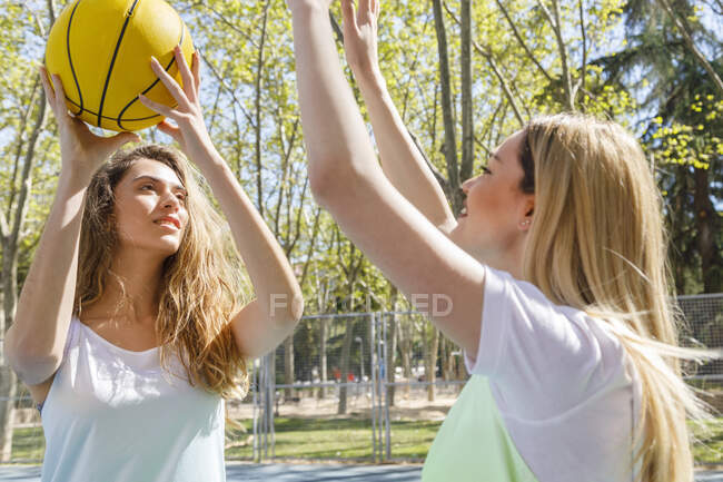 Молодые женщины играют в баскетбол в солнечный день — стоковое фото