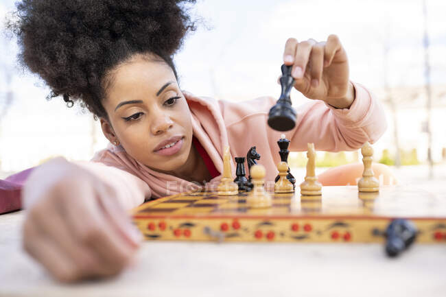 Concentrated woman playing chess while leaning on table — Stock Photo