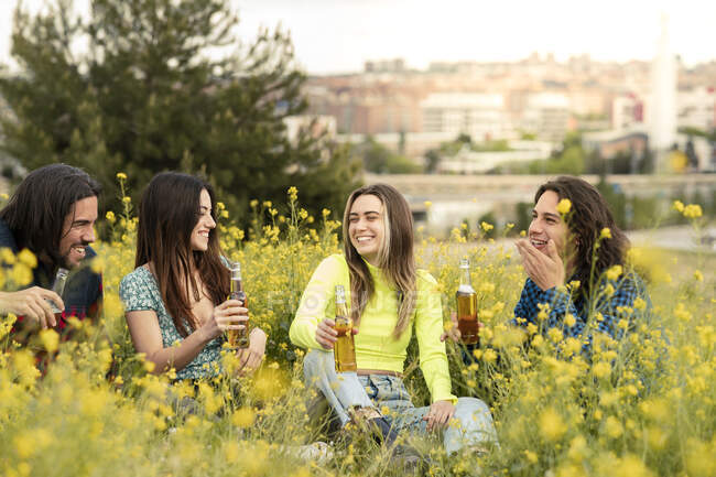 Allegro maschio e femmina amici avendo birra sul campo — Foto stock