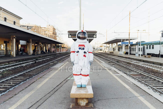 Joven astronauta de pie en el banco de la estación de ferrocarril - foto de stock