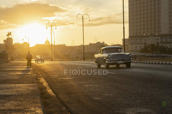 Carros se movendo na estrada na cidade durante o pôr do sol — Fotografia de Stock