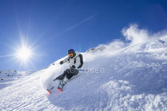 Солнце светит над молодым человеком, катающимся на лыжах в массиве Арльберг — стоковое фото