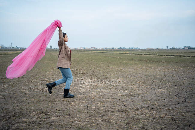 Женщина бежит с розовой сеткой тюля на поле — стоковое фото