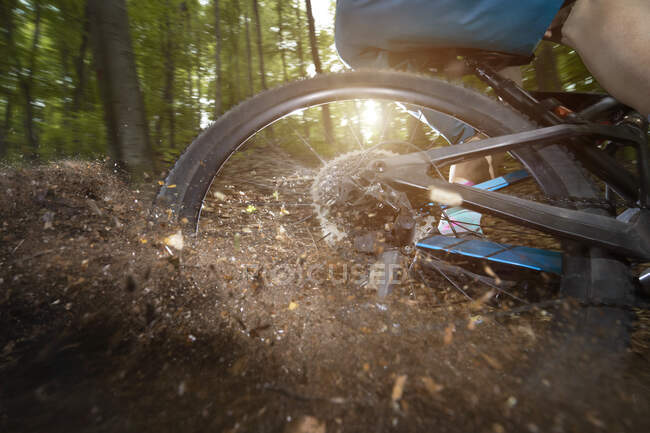 Rear wheel of bicycle drifting in dirt road at forest — Stock Photo
