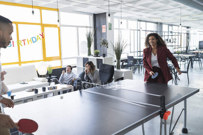 Smiling businesswoman playing ping pong with male colleague at coworking office — Stock Photo