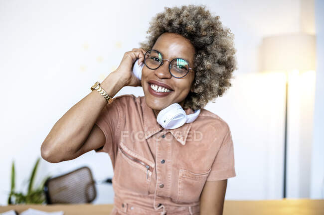 Femme d'affaires avec des lunettes tenant des écouteurs au bureau à domicile — Photo de stock