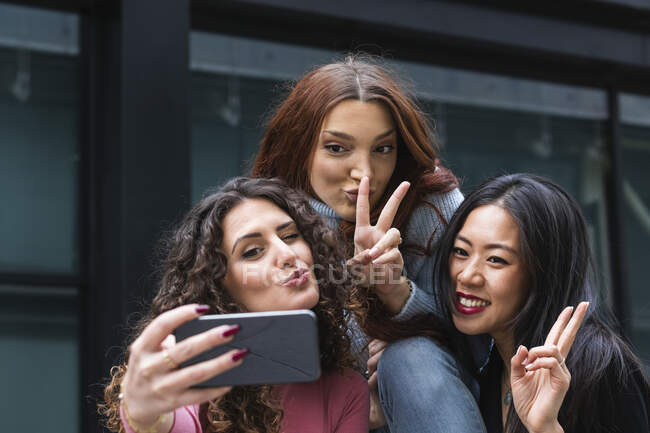 Jeune femme rondeur tout en prenant selfie sur téléphone mobile avec des amis — Photo de stock