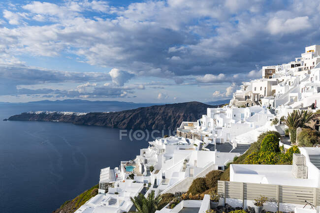 Grecia, Santorini, Fira, Nubes sobre casas blancas de la ciudad situada en  el borde de la caldera costera — Mar Egeo, Orden - Stock Photo | #492513098