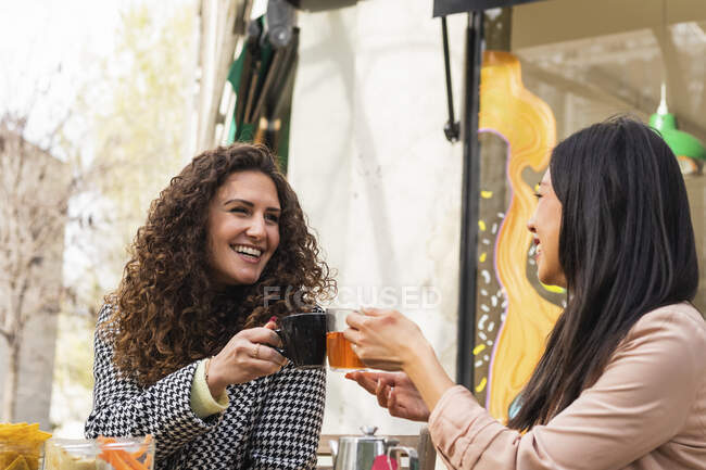 Donne sorridenti brindare bere al caffè marciapiede — Foto stock