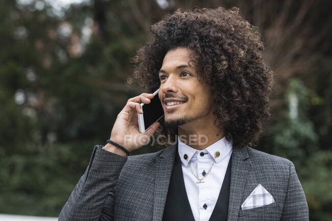 Sonriente joven hombre de negocios en anillo nasal hablando a través del teléfono móvil - foto de stock