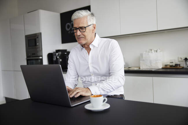 Mature professional working on laptop in cafeteria — Stock Photo