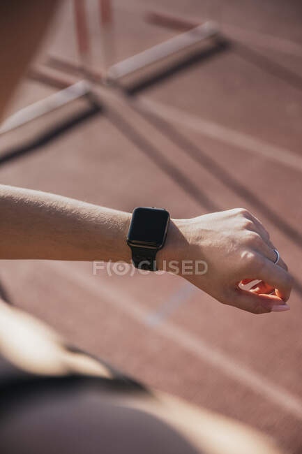 Sportswoman controllare orologio intelligente durante la giornata di sole — Foto stock