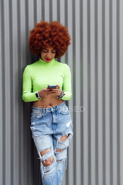 Donna alla moda utilizzando il telefono cellulare davanti all'otturatore — Foto stock