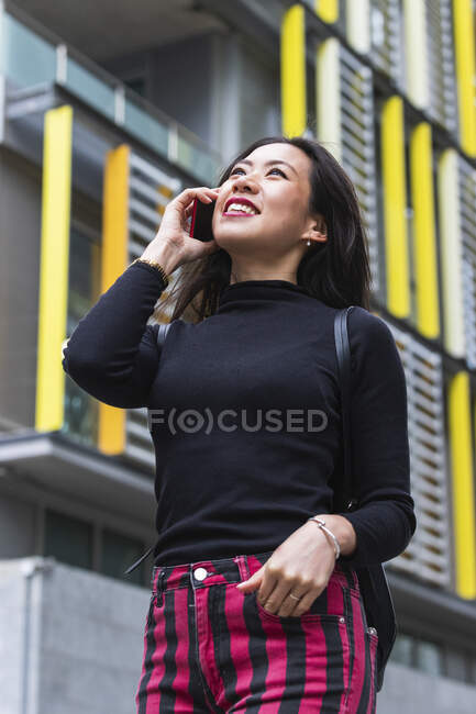 Щаслива жінка відвернулася, розмовляючи по мобільному. — стокове фото