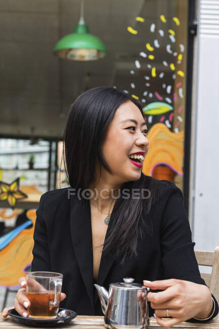 Cheerful young female at sidewalk cafe — Stock Photo