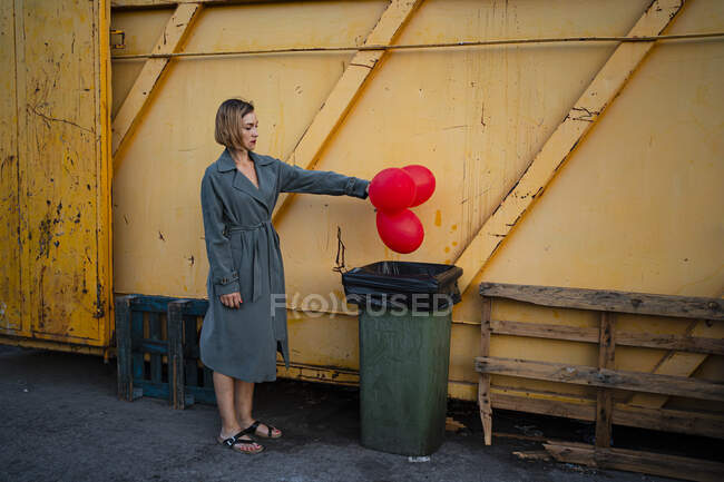 Mitte erwachsene Frau wirft Luftballon in Mülleimer — Stockfoto