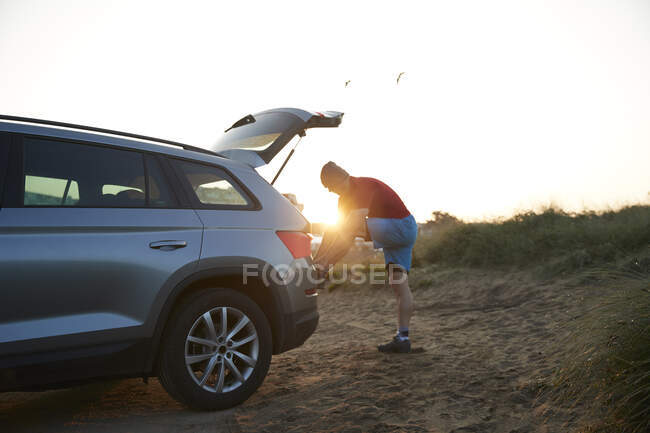 Sportsman tying shoelace at car trunk — Stock Photo