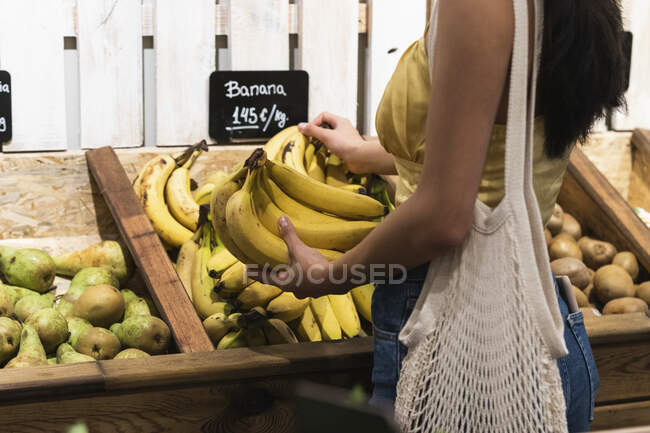 Mulher escolhendo bananas no supermercado — Fotografia de Stock