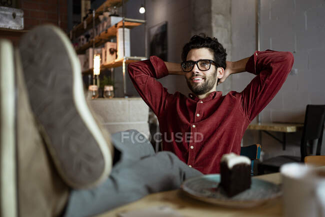 Homme d'affaires reposant jambe sur la table tout en rêvant jour dans un café éclairé — Photo de stock