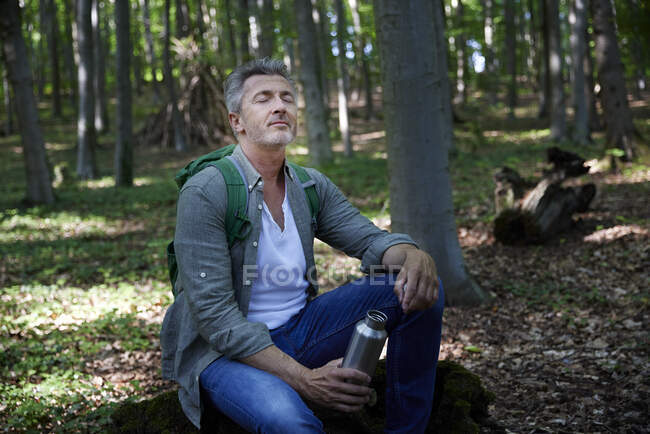 Людина тримає пляшку води в лісі. — стокове фото