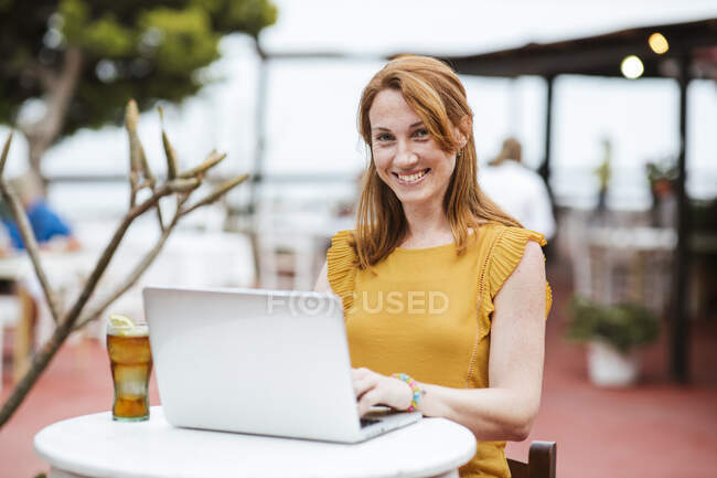 Freiberuflerin sitzt mit Laptop und Getränk an der Bar — Stockfoto