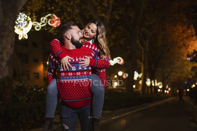 Man piggybacking woman during Christmas at night — Stock Photo