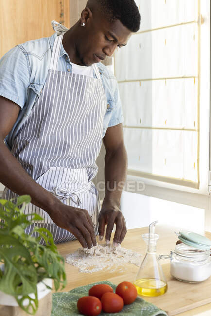 Junger Mann knetet Teig für Pizza in Küche zu Hause — Stockfoto