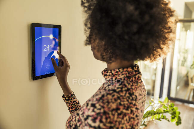 Femme ajustant la température sur thermostat intelligent à la maison — Photo de stock