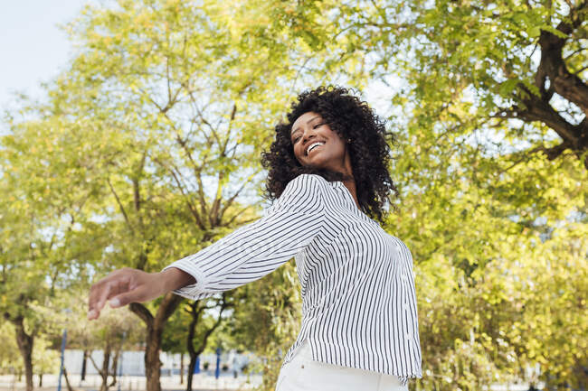 Glückliche Frau mit lockigem Haar tanzt im Park — Stockfoto