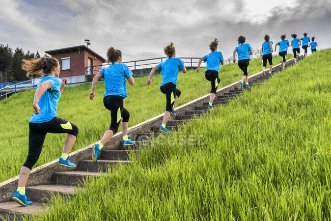 Mujer joven corriendo en los escalones cerca de la hierba durante el día - foto de stock