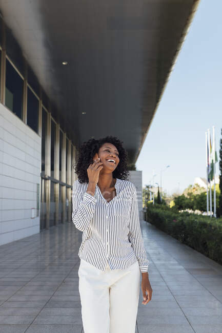 Junge Frau lacht beim Telefonieren vor Bürogebäude — Stockfoto