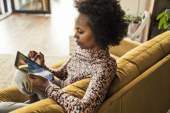 Frau untersucht Pulsspuren auf digitalem Tablet im Sitzen auf Sofa — Stockfoto