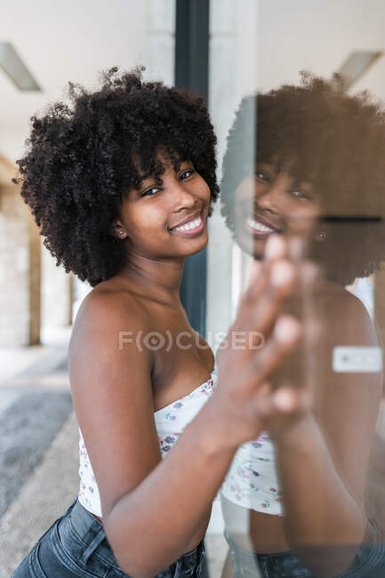 Sorridente giovane donna appoggiata su vetro — Foto stock