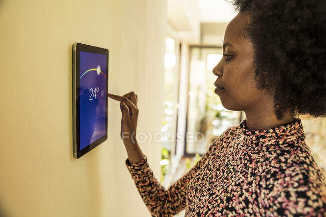 Afro woman using home automation device on wall — Stock Photo