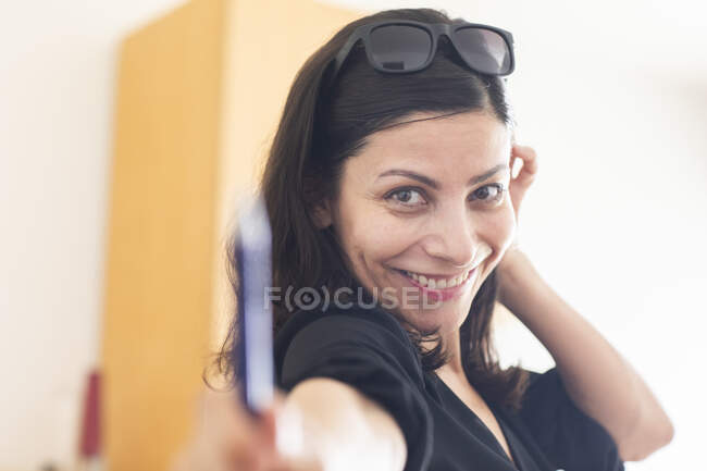 Счастливая деловая женщина в солнцезащитных очках дает ручку, стоя на посту — стоковое фото