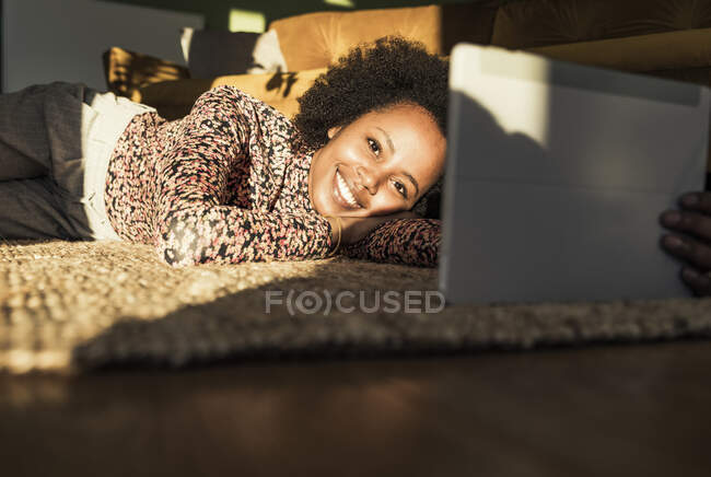 Femme souriant tout en utilisant une tablette numérique à la maison — Photo de stock