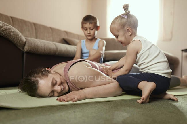 Son and daughter massaging mother's back on exercise mat at home — Stock Photo
