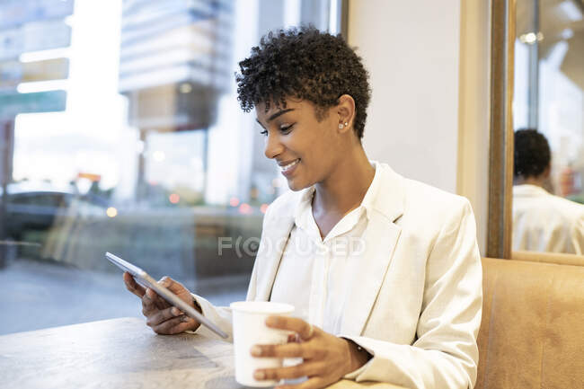 Mujer de negocios usando tableta digital mientras está sentado en la cafetería - foto de stock