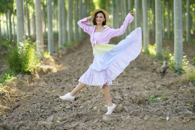 Lächelnde junge Frau mit Hut tanzt im Wald — Stockfoto