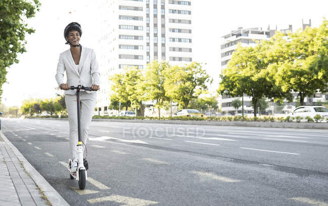 Счастливая женщина пригородного электрического самоката на улице в городе — стоковое фото