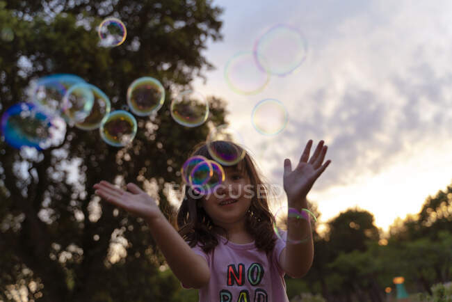 Ragazza che gioca con bolle di sapone durante il tramonto — Foto stock