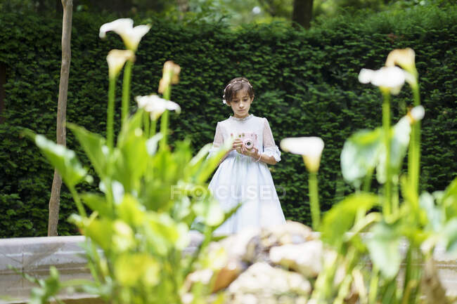 Ragazza in abito bianco comunione con macchina fotografica al parco — Foto stock