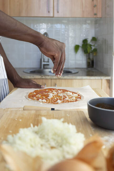 Mann toppt Pizza mit gehackten Zwiebeln in Küche zu Hause — Stockfoto