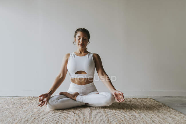 Female fitness teacher meditating in lotus position at yoga studio — Stock Photo