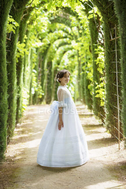 Усміхнена мила дівчинка в білій комірчині в саду. — стокове фото