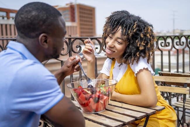 Man and woman eating fruit salad while sitting in balcony — Stock Photo
